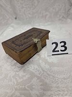 Closed Bible showing embossed leather cover, brass clasp, page edges wear