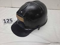 Left-front view of black MSA Comfo Cap with brass lamp plate