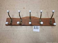 Full view of coat rack showing five hooks, wood base, size reference