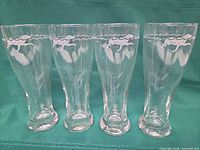 Four clear pilsner glasses in a row