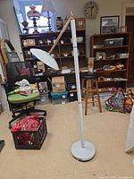 Front view of white halogen torchiere floor lamp showing articulating dish shade and pole