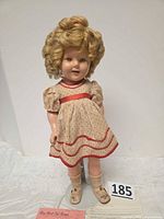 Full-length view of doll on stand showing outfit and overall condition