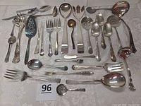 Full spread of all silver plate utensils laid out on tablecloth