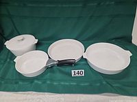 Full set of four white Corning Ware pieces, lid on one, handle attached to one