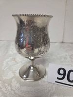Silver plated chalice front view showing floral etching, beaded rim, stem, foot