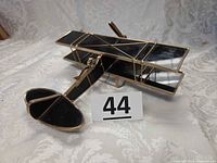 Left front view of stained glass biplane showing black glass panels and gold-tone framework