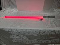 Full view lightsaber illuminated red on white cloth