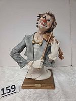 Front view of porcelain clown violinist on wooden base