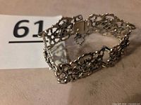 Bracelet laid flat showing filigree design, clasp, and safety chain