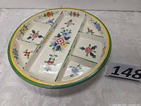 Top view of round five-section porcelain dish showing floral decoration and coloured rims