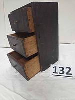 Front angled view showing three drawers partially open, dark exterior, metal knobs