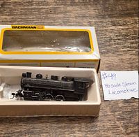 Locomotive resting in foam insert with Bachmann HO box behind and handwritten lot note