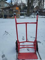 Rear view of red steel hand truck standing on snow