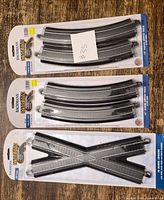 Three sealed Bachmann E-Z Track HO scale packs: two curved track packs, one X-crossing pack