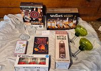 All barware items laid out on sheet including boxed sets, book, tin, and loose glasses