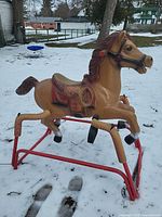 Full view of plastic horse on red spring frame in snow