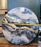 Full view of round artwork leaning against cabinet