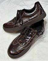 Side and top view of both sneakers to show leather, woven panels, sole height