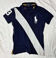 Full view of front showing stripe, logo, sleeve patch, and overall condition
