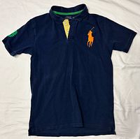 Front view showing navy color, orange logo, yellow placket detail