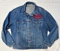 Front view of denim jacket showing chest logo patch, pockets and button closure