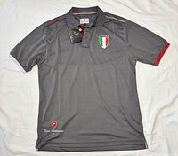 Front view of grey polo showing Spyder crest, tags, collar trim, lower shield patch