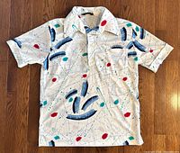 Full front view of polo shirt laid flat displaying overall print, collar, pocket and sleeves