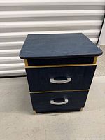 Front three-quarter view of blue nightstand showing two drawers and handles