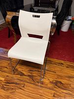 Front view of white Duet armless chair showing seat, back cutout handle, chrome sled base