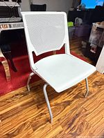 Front view of white perforated seating surface and backrest on metal frame