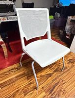 Front three-quarter view of white Haworth Very bar-height stacking stool showing perforated back, solid seat, and sled base