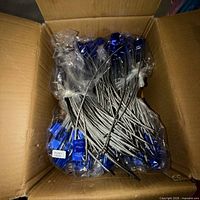 Open carton showing numerous blue-headed cable seals bundled in plastic