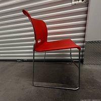 Right side view of red plastic chair with chrome sled base