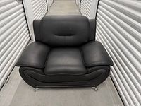 Full front view of black faux leather armchair in storage unit