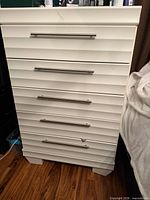 Front view of white ribbed five-drawer dresser with metal pulls