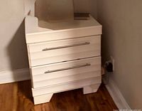 Front view of white two-drawer nightstand showing handles and legs