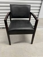 Front view of wooden chair with black leather seat and back