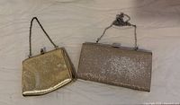 Both gold evening clutches showing comparative sizes and chains