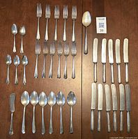 Full layout of all 35 flatware pieces on wooden surface