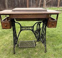 Front view showing cabinet top, cast-iron base, two drawers, treadle