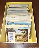 Box filled with sorted postcard bundles labeled England, Scotland, Ireland