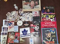 Entire lot laid out showing cards, pucks, cups, magazines, jersey, patches, stamp folder, skate figurine