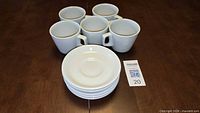 Stacked saucers in foreground with five coffee cups behind