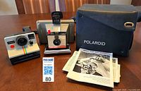 Both cameras, case, papers displayed on table