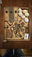 Tray showing brass backplates, porcelain knobs, brass knob set and loose antique hardware