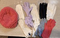 All nine glove pairs and pink crocheted hat laid out
