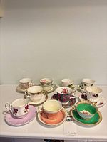 Front view of ten tea cup and saucer sets arranged on surface