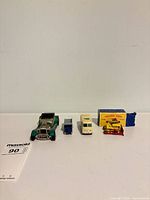 Line-up of five vehicles and box on white surface