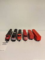 Five train pieces lined up: four locomotives and two orange boxcars