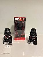 Front view showing boxed Kylo Ren bobble head flanked by two Darth Vader dispensers